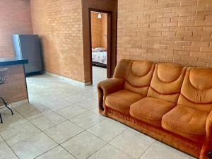 a couch sitting in a room with a brick wall at Flat de 2 quartos com AR na área central de GV com conzinha completa-garagem-wifi-Bom p grupos ou familias ou empresas in Governador Valadares