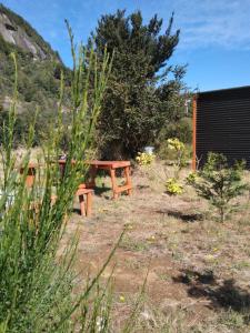 drewniany stół piknikowy i ławka w ogrodzie w obiekcie CABAÑA PARCELA VISTA HERMOSA w mieście Puerto Aisén