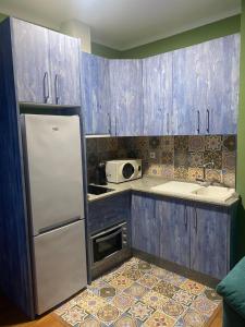 a kitchen with blue wooden cabinets and a refrigerator at Apartamento Carmona in Carmona