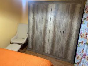 a bedroom with a wooden cabinet and a chair at Apartamento Carmona in Carmona