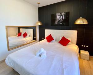 a bedroom with a large white bed with red pillows at La Vague Tendresse - Vue mer - Jacuzzi & Sauna in Le Tréport