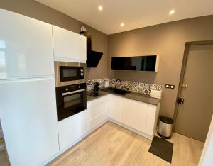 una cocina con armarios blancos y electrodomésticos negros en La Vague Tendresse - Vue mer - Jacuzzi & Sauna, en Le Tréport