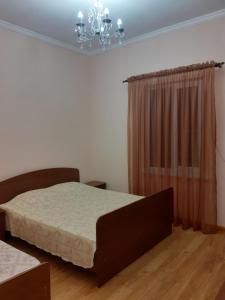a bedroom with a bed and a chandelier at U Asidy Guest House in Gudauta