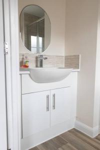 7 Swiftsure - 4 Bedroom Luxury and Spacious Home في ميلتون كينز: حمام أبيض مع حوض ومرآة