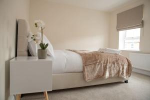 a white bedroom with a bed and a table with flowers on it at 7 Swiftsure - 4 Bedroom Luxury and Spacious Home in Milton Keynes