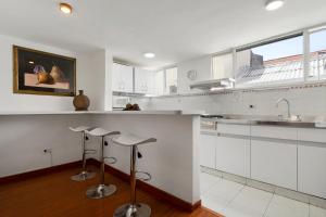 a kitchen with white cabinets and bar stools at Habitación 4 independiente con baño privado Unicentro in Bogotá