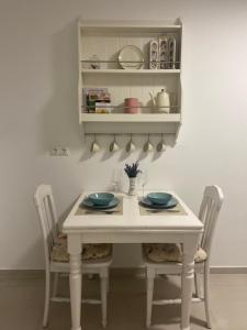 einen Esstisch mit 2 Stühlen und einen weißen Tisch mit Tellern in der Unterkunft Schöne Wohnung über Wissen in Wissen