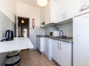 una cocina con armarios blancos, fregadero y 2 taburetes en Akisol Faro Sunny, en Faro