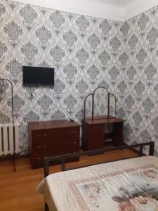 a bedroom with a bed and a tv on a wall at U Asidy Guest House in Gudauta