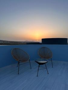 dos sillas y una mesa en un techo con la puesta de sol en Casa Nordeste con piscina Casilla de Costa, en La Oliva