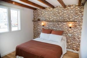 1 dormitorio con 1 cama con pared de piedra en Pension Casa Manolo en Fonsagrada