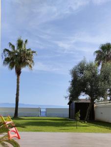 a building with two palm trees and the ocean at Camera sul Mare in Messina