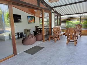 a living room with wooden chairs and a television at Casa de Campo Las Partidas in Quimbaya