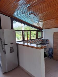 a kitchen with a white refrigerator and a wooden ceiling at Casa de Campo Las Partidas in Quimbaya