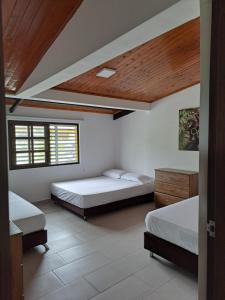 a bedroom with two beds and a wooden ceiling at Casa de Campo Las Partidas in Quimbaya +15 photos
