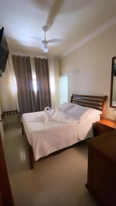1 dormitorio con 1 cama con sábanas blancas y ventilador en Espaço Nobre en Cunha