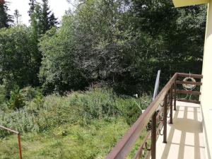 a wooden railing on a porch with trees and bushes at Útulný 3-izbový byt v srdci Tatier in Vysoké Tatry