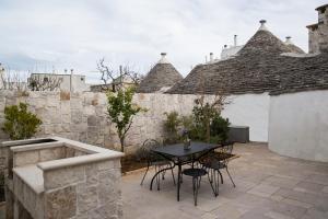 un patio con mesa, sillas y pared de piedra. en Il Trullo del viaggiatore, en Alberobello