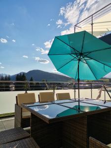 a table with a blue umbrella on a patio at Berg:Zeit_Apartments in Tamsweg