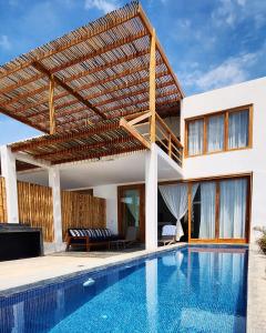 a house with a swimming pool and a wooden pergola at Casa GAIA - Punta Sal in Canoas De Punta Sal