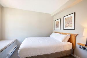 a small bedroom with a bed and two pictures on the wall at Whistler Village Centre by LaTour Hotels and Resorts in Whistler