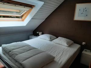 un letto con lenzuola e cuscini bianchi in una camera da letto di De Bosdreef - Hengelhoef - duplex met verwarmd openluchtzwembad ad Aan de Wolfsberg