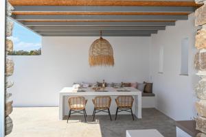 una sala da pranzo bianca con tavolo e sedie bianchi di Xerolithia suites a Agios Sostis