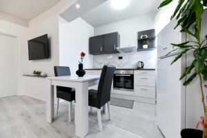 uma cozinha branca com uma mesa e cadeiras brancas em Apartment Lusy Lo em Zadar