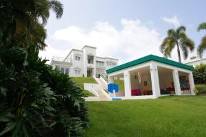 une grande maison blanche avec un toit vert dans l'établissement Campestre para familias grupos en Puerto Rico, à Luquillo