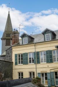 ein altes Haus mit einem Turm und grünen Fensterläden in der Unterkunft La Mondaine - idéalement situé, charme in Honfleur