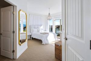 a white bedroom with a bed and a mirror at The Beach House at Barona Beach 4301 in West Kelowna +27 photos
