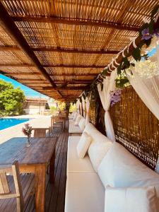 a pergola with white pillows and a wooden table at Pousada Vila Dendê in Trancoso