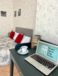 un ordenador portátil sentado en una mesa junto a una cama en Rome Open City Home en Roma