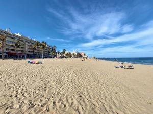 a beach with people sitting on the sand and the ocean at Casas Holiday - Puerto Romano in La Mata