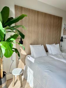 a bedroom with a white bed and a plant at Oranje Nassau aan Zee Appartement in Zandvoort