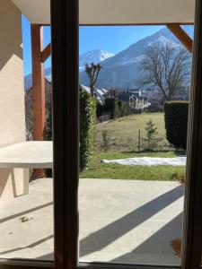 widok na góry przez szklane drzwi w obiekcie Appartement Val de Roland w mieście Luz-Saint-Sauveur +1 zdjęcie
