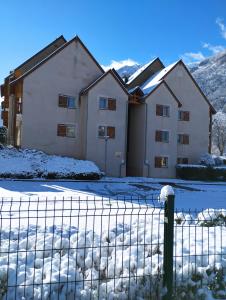 dom z płotem w śniegu w obiekcie Appartement Val de Roland w mieście Luz-Saint-Sauveur