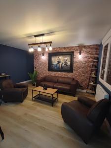 - un salon avec des canapés et un mur en briques dans l'établissement Le Gîte de Daisy, à Saint-Côme-du-Mont