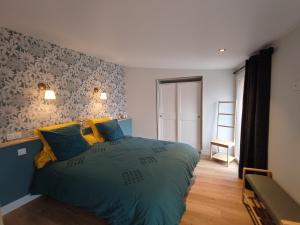 - une chambre dotée d'un grand lit avec des oreillers bleus et jaunes dans l'établissement Le Gîte de Daisy, à Saint-Côme-du-Mont