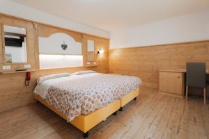 a bedroom with a bed and a desk and a window at Hotel Edelweiss in Val di Zoldo