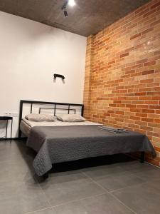 a bed in a room with a brick wall at Loft на Кониського, центр in Dnipro