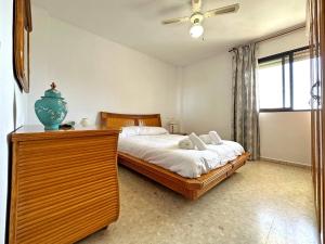 ein Schlafzimmer mit einem Bett und einer Kommode mit einer Vase darauf in der Unterkunft Apartamento Carihuela Beach Experience in Torremolinos