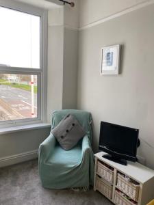 a living room with a chair and a television at Central en-suite double room in Plymouth