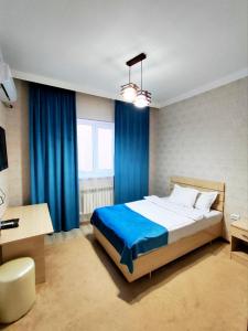 a bedroom with a large bed with blue curtains at Asem Hotel in Nukus
