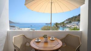a wooden table with chairs and an umbrella on a balcony at Villa Niki in Loutro