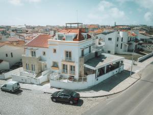 a large white house with a car parked in front of it at PKSC Surf House in Peniche