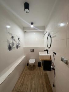 a white bathroom with a toilet and a sink at Apartamenty Prosta - Podmurna in Toruń