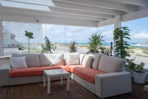 a living room with a couch and a large window at PKSC Surf House in Peniche