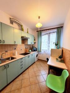 a kitchen with a table and a green chair at Mini apartament in Łańcut