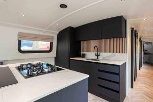 a kitchen with black cabinets and a sink and a stove at The Vätten Hüs A Luxury/VIP boat in Manchester